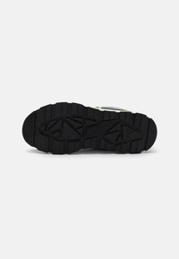 Black rubber shoe sole with a textured tread pattern, featuring angular designs and ridges for grip and stability.
