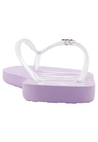 Violetti flip-flop, jossa on teksturoitu pohja ja läpinäkyvät remmit. Jalkatuki on hieman kaareva mukavuuden vuoksi ja säilyttää minimalistisen muotoilun.