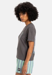 Gray cotton t-shirt with a relaxed fit, short sleeves, front and back graphic designs, paired with light green striped shorts.