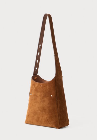 Bolso de hombro de ante marrón con una sola correa de cuero ajustable, que presenta una textura suave, un diseño minimalista y detalles metálicos.