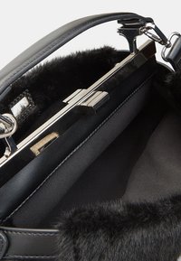 Borsa nera con interno foderato in pelliccia, hardware argentato elegante e forma strutturata. Presenta un esterno lucido e una maniglia robusta.
