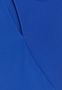 Gros plan sur un tissu bleu avec une texture fine côtelée et un détail de couture superposé.