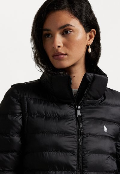 Schwarze Steppjacke mit hohem Kragen, strukturierter Oberfläche und Reißverschluss. Verfügt über ein kleines weißes Logo auf der linken Brust.