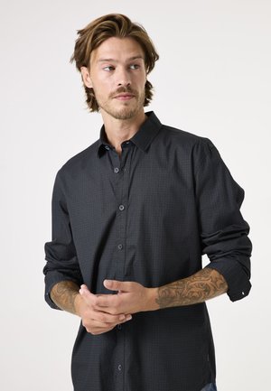 Zwarte shirt met knoopsluiting en subtiele textuur, met lange mouwen, voorzien van een gespreide kraag en blauwe knopen.