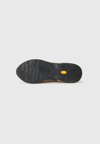 Black rubber shoe sole with a textured surface, featuring a clear tread pattern and a yellow accent logo in the center.