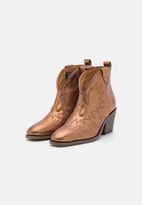 Bottines en cuir bronze avec un bout pointu et des coutures de style cowboy. Elles sont équipées de tirettes et d'un talon en bois empilé.