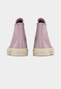 Ζευγάρι ροζ sneakers ψηλού τύπου με μοτίβο φίδιου δέρματος, μπεζ σόλες και λογότυπο Converse All Star στη φτέρνα, σε θέαση από πίσω.