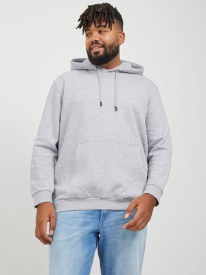 Grauer Hoodie mit einer vorderen Kängurutasche, Kapuze mit Kordelzug und gerippten Bündchen. Tragen mit hellblauen Jeans vor einem neutralen Hintergrund.