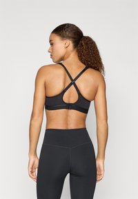 Sutien sport negru cu design încrucișat pe spate, bretele ajustabile și o textură netedă. Prezintă o închidere cu cârlig și cusături contrastante pe bandă.