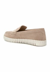 Mocasines de ante en beige claro con una suela de goma blanca. Presentan una puntera redondeada y detalles de costura a lo largo de la parte superior y los lados.