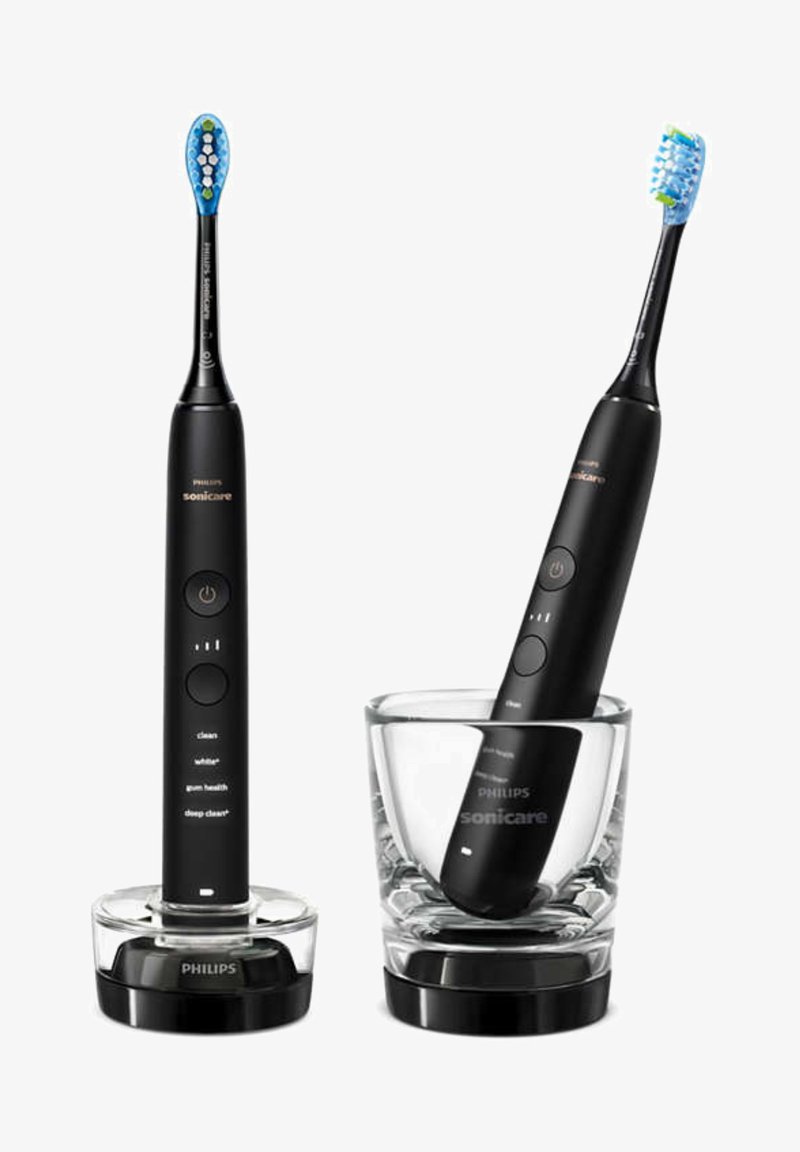 Spazzolino elettrico nero con setole blu e pulsanti sul manico, esposto in un portaspazzolino in vetro trasparente. Include una base di ricarica.