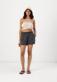 Shorts en coton gris avec une taille élastique, associés à un crop top en maille crème avec une rayure violette. Tenue décontractée dans l'ensemble.