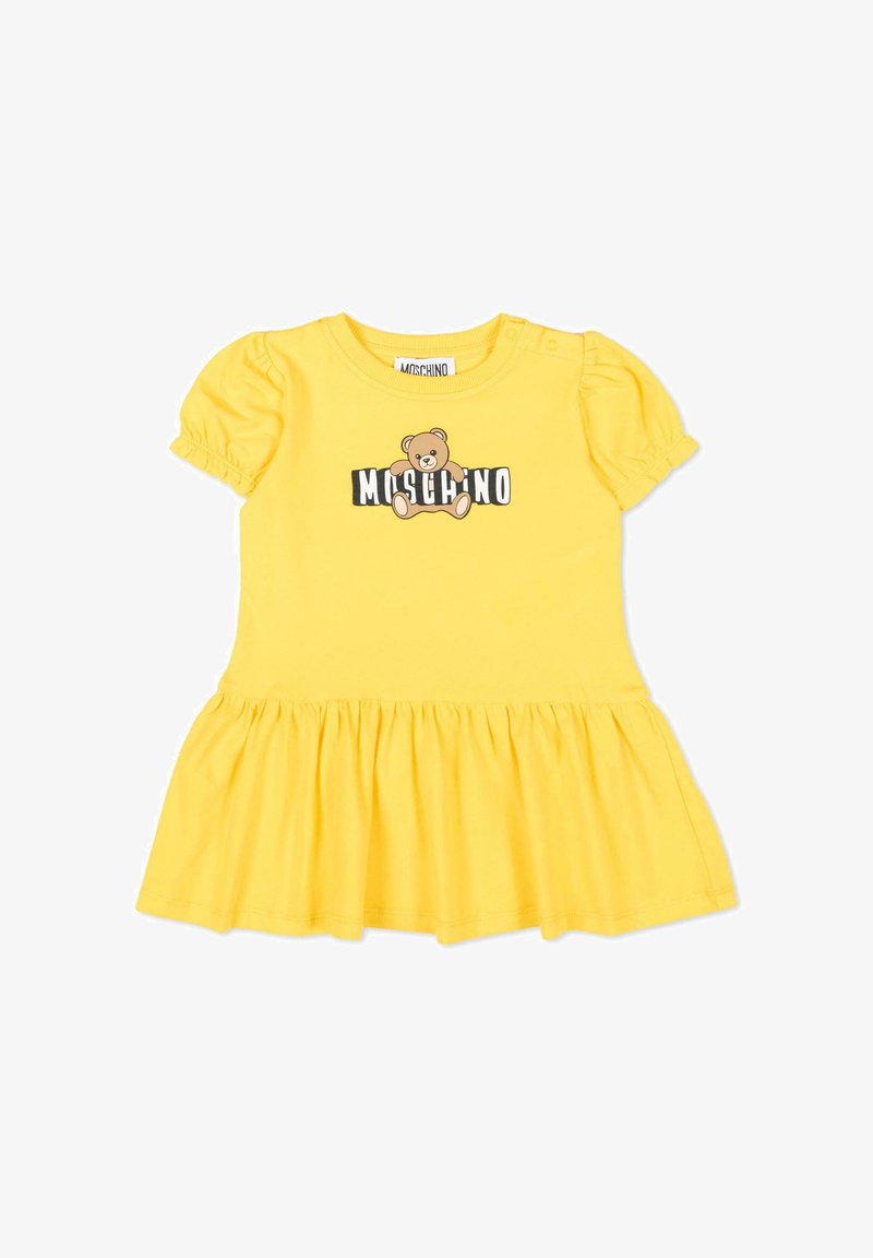 Geel babyjurkje met korte mouwen, opstaande mouwen, geplooide rok en een teddybeerlogo met de tekst "MOSCHINO" op de borst.