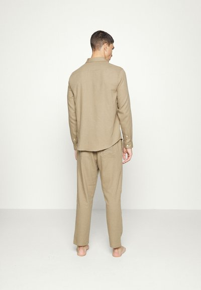 Conjunto de roupa de casa bege, apresentando uma camisa de botão de manga longa e calças combinando, feitas de um tecido suave com um corte relaxado.