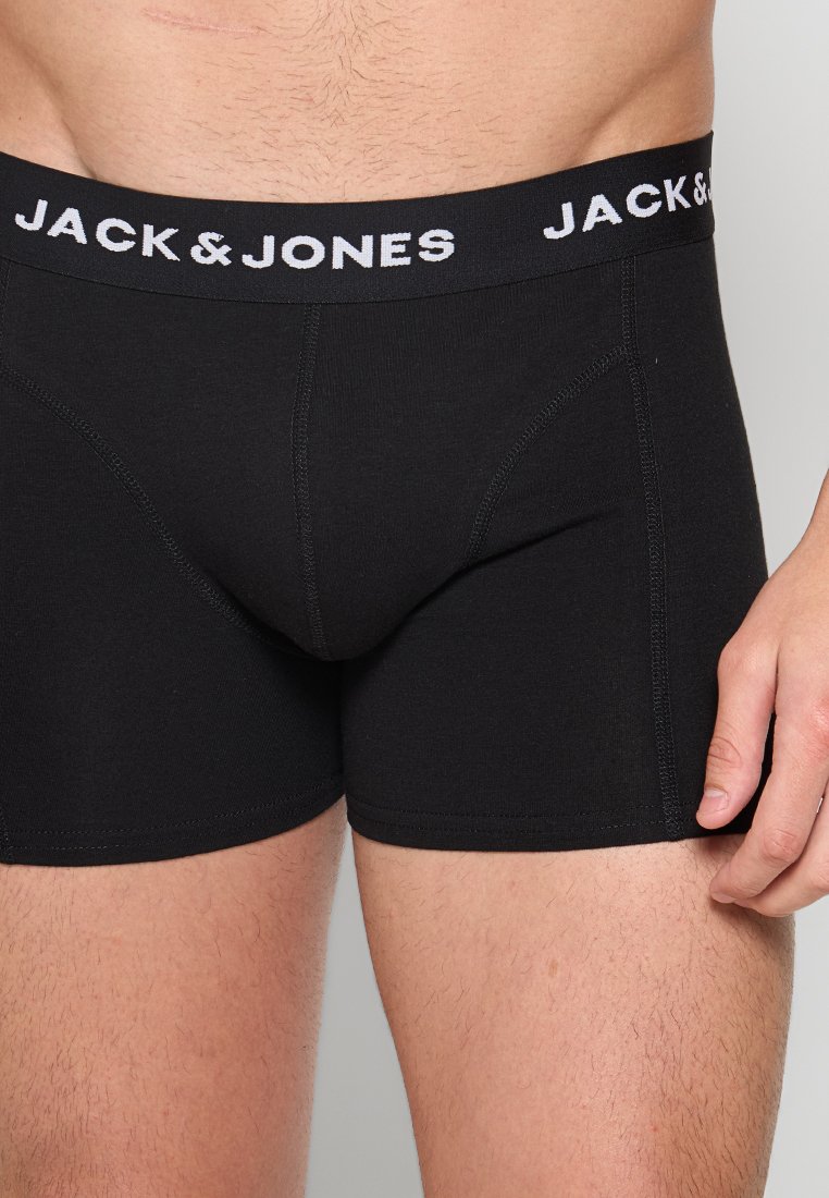 Mann trägt schwarze Jack & Jones Boxer-Shorts mit einem weißen Logo am Bund und steht mit einer Hand entspannt an seiner Seite.