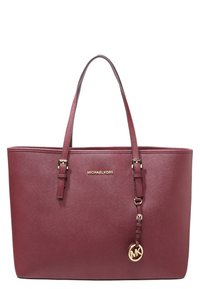 Bordeauxfarvet tote-taske lavet af tekstureret syntetisk materiale, med dobbelt håndtag, logo i guldfarve og en rund MK-charm vedhæftet.