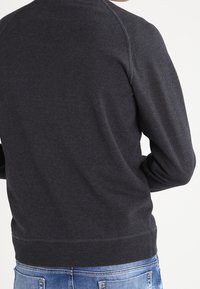 Mörkgrå sweatshirt med rund halsringning, ribbad muddar och midjesöm; mjukt tyg med en slät yta, med raglanärmar.