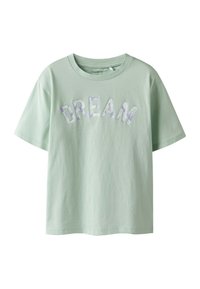 T-shirt à manches courtes vert clair en coton, présentant le mot "DREAM" en lettres texturées et à motifs sur le devant. Design classique à col ras du cou.