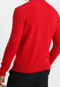 Roter Pullover aus glattem Strick, mit langen Ärmeln, rundem Halsausschnitt und geripptem Saum. Eng anliegend geschnitten.