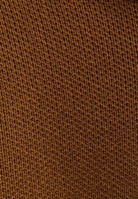 Knitted fabric in a warm brown color, featuring a textured, uniform pattern with visible stitching, creating a soft, cozy appearance.