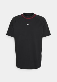 Černé tričko s krátkým rukávem Nike s malým bílým logem swoosh na hrudi a červeným lemem kolem výstřihu.