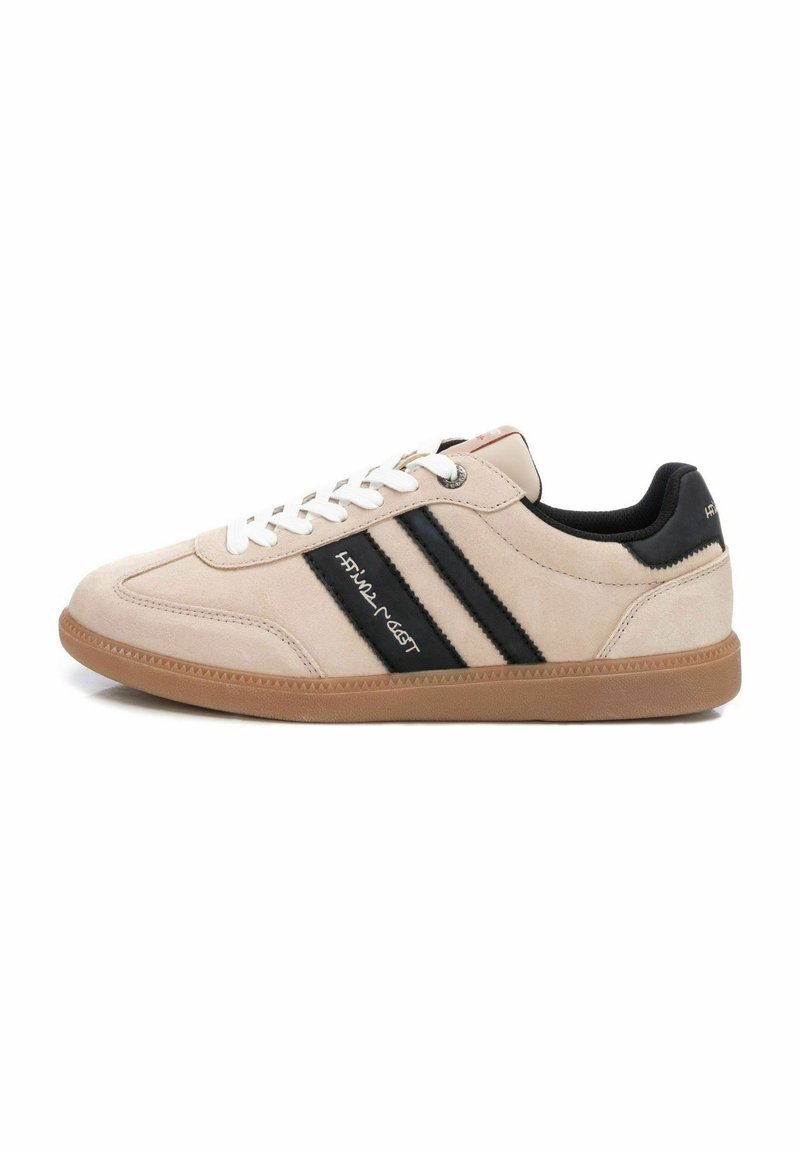 Sneaker beige in suede con strisce nere, lacci bianchi e suola in gomma. Presenta una punta tonda e un rivestimento in tessuto morbido.