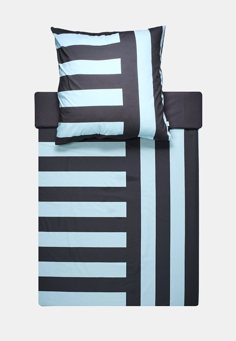 Ensemble de literie avec une base bleu marine foncé et des rayures bleu clair alternées sur la housse de couette et l'oreiller, texture en coton lisse.