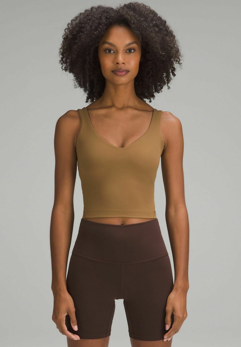 Pruun lühike tipp V-kaelusega ja paksude rihmadega, kombineeritud kõrge vöökohaga pruunide lühikestega. Sile, elastne kangas ja sobiv disain.