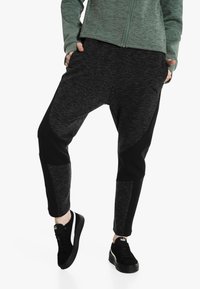 Black and dark gray jogger pants with a tapered fit, featuring contrasting panel design, soft texture, and ribbed accents on the knees.