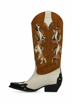 Brown suede western boot featuring white and black accents with a pointed toe. Decorative snake-pattern cutouts on the shaft. Block heel.