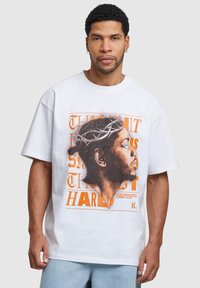 Hvid bomulds t-shirt med et stort grafisk motiv af en profil med en tornekrone og orange tekst. Casual pasform med korte ærmer.