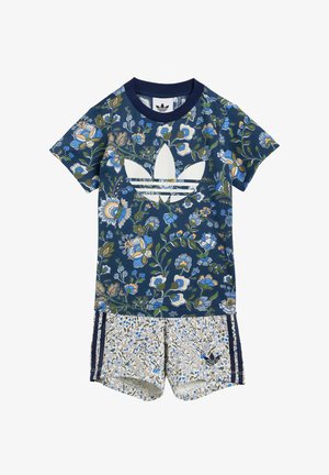 Jersey-set met bloemmotieven, bestaande uit een marineblauwe T-shirt met wit logo en gemusterde shorts met lichte achtergrond en blauwe accenten.