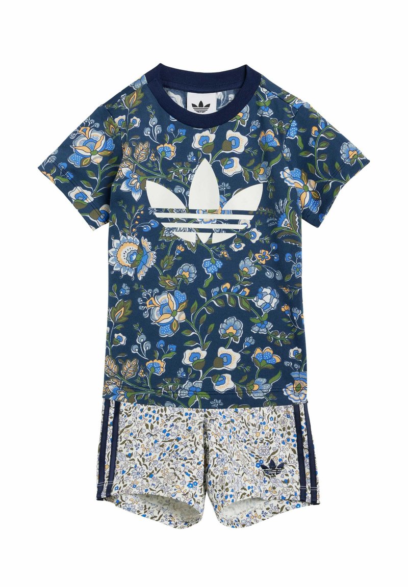 Completo in jersey con motivo floreale, composto da una maglietta blu navy con logo bianco e pantaloni corti a fantasia con sfondo chiaro e dettagli blu.