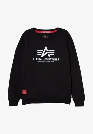 Sudadera negra con cuello redondo, con un logo blanco de "Alpha Industries" y una pequeña etiqueta roja en el dobladillo. Tejido suave, diseño simple.