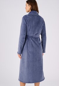 Lunga veste blu realizzata in un morbido tessuto testurizzato con un motivo a spina di pesce, dotata di una cintura e di un colletto.