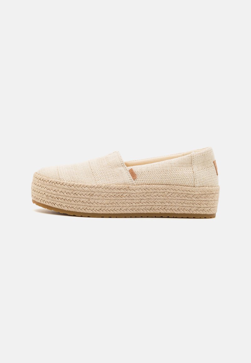 Scarpe beige senza lacci realizzate in tessuto intrecciato con una superficie testurizzata e una suola in giute intrecciato. Design minimalista con piccole rifiniture.