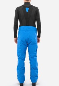 Schwarzes Langarmoberteil mit strukturiertem Rücken und blauen Schneeanzugshosen, die eine glatte Oberfläche, einen verstellbaren Bund und Reißverschlussdetails an den Beinen aufweisen.