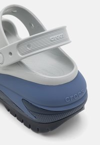 Vit och marinblå Crocs sandal med bred rem, tjock sula, texturerad fotbädd och logotypdetalj, med kontrasterande lager och rundad häl.