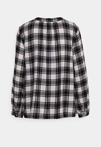 Camicia a maniche lunghe bianca e nera a scacchi, con scollatura rotonda, tessuto morbido e dettagli arricciati sulla schiena e sui polsini.