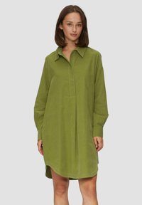 Grünes Cordhemdkleid mit einem kragenlosen Ausschnitt, langen Ärmeln und einer Vorderknopfleiste. Es hat eine lockere Passform und einen gerundeten Saum.