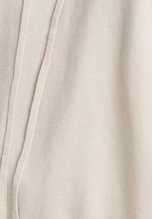 Beige Strickstoff mit einer weichen Textur, der an einer Seite eine vertikale Naht aufweist. Das Design ist einfach und minimalistisch.