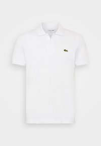Polo blanc en coton avec une patte de boutonnage à trois boutons et des manches courtes. Présente un petit logo Lacoste vert sur la poitrine gauche.