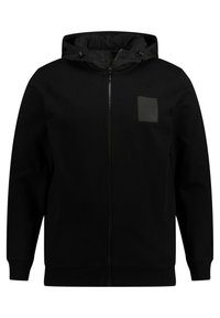 Felpa nera con zip in tessuto testurizzato, cappuccio regolabile con cordini e una sottile toppa del logo in rilievo sul petto.