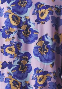 Tela de estampado floral en tonos de azul, púrpura y dorado sobre un fondo lavanda. Material texturizado con grandes formas de flores abstractas.