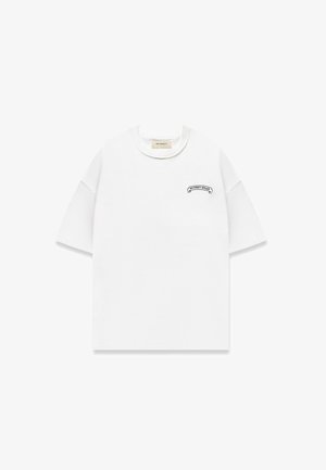Camiseta blanca texturizada de manga corta con cuello redondo y un pequeño logo negro "RETERNITY ATELIER" en el lado izquierdo del pecho.