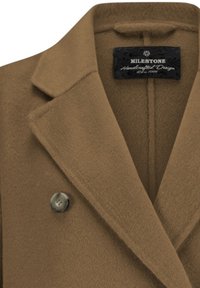 Brauner Wollmischmantel mit tailliertem Kragen, featuring ein doppelreihiges Design und ein großes Knopfdetail. Schwarzes Etikett sichtbar im Inneren.