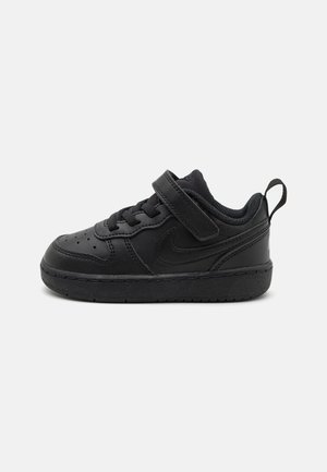 Black sneaker with a smooth leather upper, round toe, lace-up front, Velcro strap, and textured rubber sole. Features perforations for breathability.
