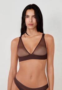 Bralette inalámbrico marrón con parte superior de malla transparente, diseño en V, tirantes ajustables y banda de tela suave. Sin almohadillas ni aros.