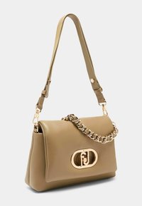 Beżowa skórzana torebka z płaskim korpusem, wyraźnie zarysowanym kształtem, złotym łańcuszkiem oraz owalnym logo z przodu. Regulowany pasek.