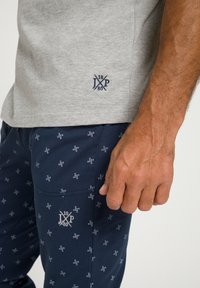 Grå bomulds T-shirt med marineblåt logo, parret med marineblå bukser med et gentaget mønster og broderet logo på lommen.